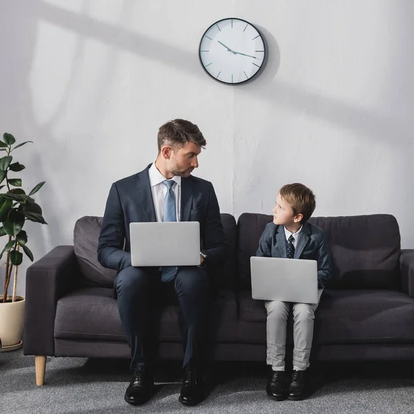 Serious Businessman His Son Formal Wear Sitting Sofa Laptops Looking — Stock Photo, Image