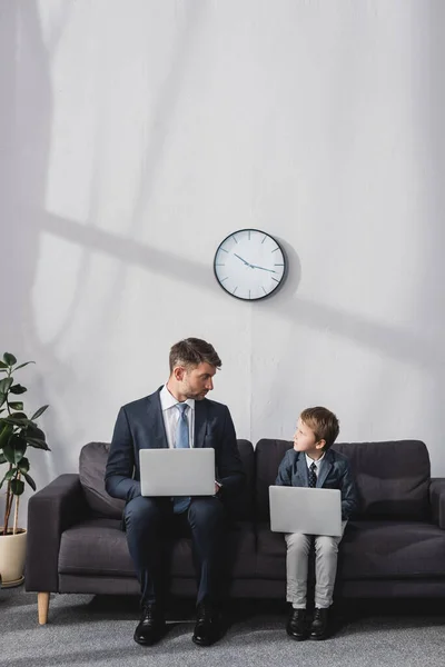 Serious Businessman His Son Formal Wear Sitting Sofa Laptops Looking — Stock Photo, Image