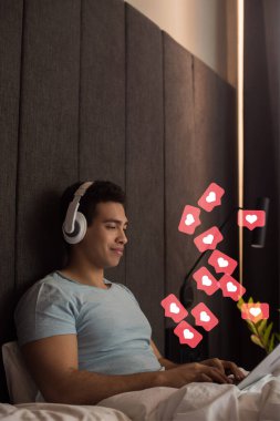 Kulaklıkla müzik dinleyen ve yatak odasındaki gibi sanal kalplerin yanında dizüstü bilgisayar kullanan ırkçı bir adam. 