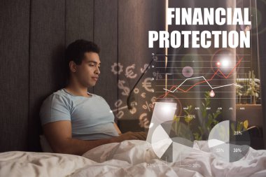 Finansal koruma mektupları, para tabelaları, grafikler ve grafikler yanında dizüstü bilgisayar kullanan yakışıklı melez serbest ırk.  