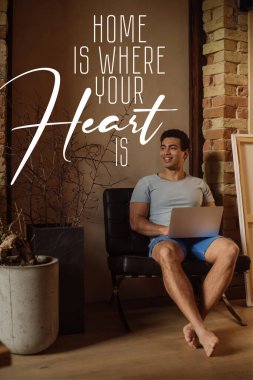 happy mixed race freelancer chilling with laptop near lettering home is where your heart is lettering  clipart