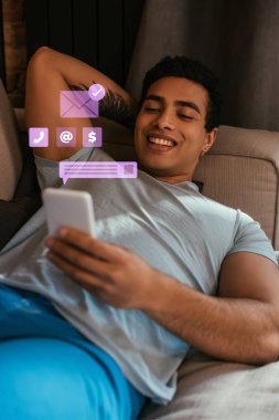 Seçici odak noktası karışık ırk adamının sanal konuşma baloncuğu ve zarfın yanında yeni mesaj illüstrasyonuyla birlikte akıllı telefon kullanması. 