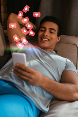 Seçici odak noktası melez bir adamın sanal kalplerin yanında dinlenmesi ve akıllı telefon kullanması. 