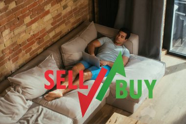 Karışık ırk serbest çalışanı dizüstü bilgisayar kullanıyor ve satılık mektupların yanındaki kanepede takılıyor. 