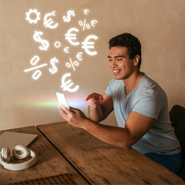 счастливый смешанный гонщик указывая пальцем на смартфон, ноутбук, наушники и денежные знаки
 