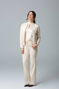 Gri arka planda kameraya bakan güzel bir iş kadını.