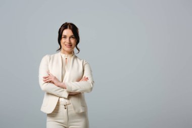 Kollarını kavuşturup kameraya gülümseyen güzel bir iş kadını. Griye izole edilmiş, vücut pozitifliği kavramı. 