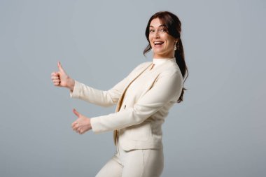 Güzel gülümseyen iş kadınının Griler 'de baş parmaklarını göstermesi. 