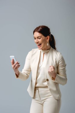 Neşeli iş kadını, gri renkte akıllı telefon tutarken, evet jest yapıyor. 