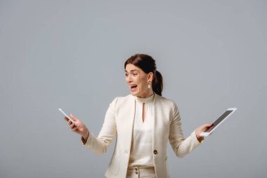 Akıllı telefon ve dijital tablet taşıyan korkmuş iş kadını gride izole edildi 