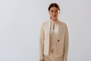 Resmi giyinmiş güzel esmer kadın gri renkli kameraya bakıyor. 