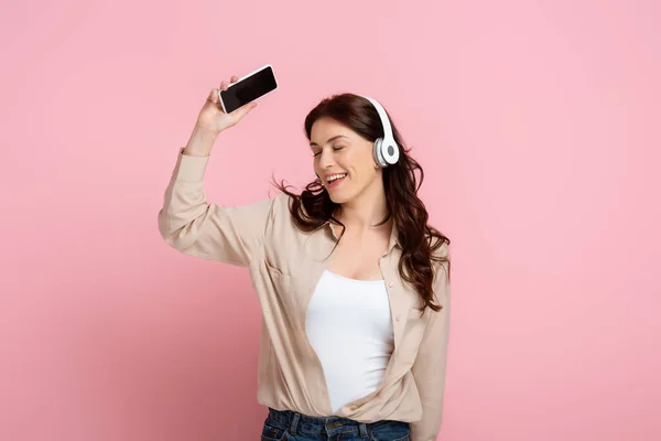 Χαμογελαστή Γυναίκα Στα Ακουστικά Κρατώντας Smartphone Κενή Οθόνη Ροζ Φόντο — Φωτογραφία Αρχείου