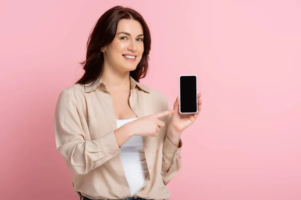 Mujer Sonriente Apuntando Con Dedo Teléfono Inteligente Sobre Fondo Rosa — Foto de Stock