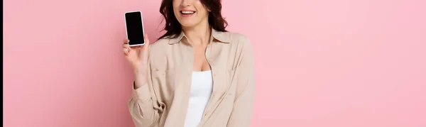Panoramiczne Ujęcie Uśmiechniętej Kobiety Pokazujące Smartfona Pustym Ekranem Różowym Tle — Zdjęcie stockowe
