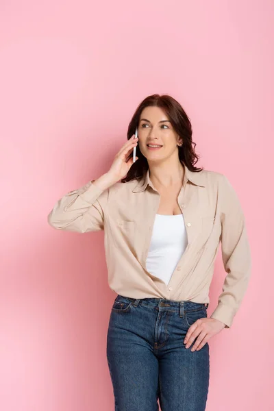 Aantrekkelijke Brunette Vrouw Glimlachen Tijdens Het Praten Smartphone Roze Achtergrond — Stockfoto