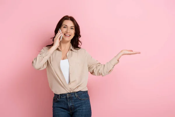 Mulher Sorridente Bonita Apontando Com Mão Enquanto Fala Smartphone Fundo — Fotografia de Stock