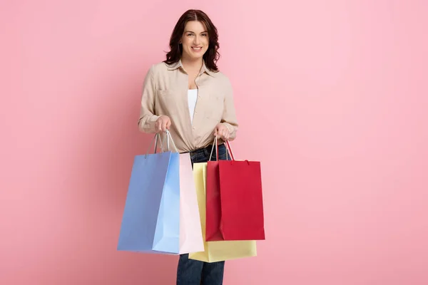 Mulher Bonita Sorrindo Enquanto Segurando Sacos Compras Coloridos Fundo Rosa — Fotografia de Stock