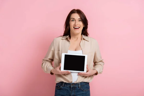 快乐的女人拿着空白屏幕的数码平板电脑 看着粉色背景的相机 — 图库照片