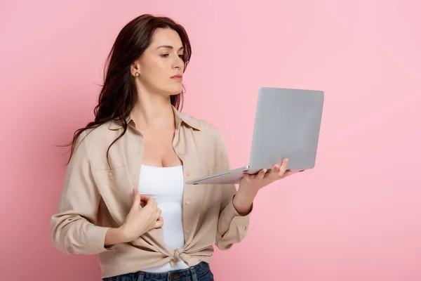 漂亮的黑发女人 带着粉色背景的笔记本电脑 — 图库照片