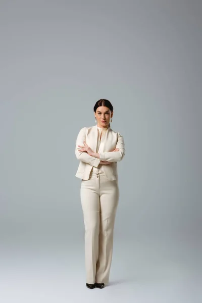 Beautiful woman in formal wear with crossed arms looking at camera on grey background, concept of body positive