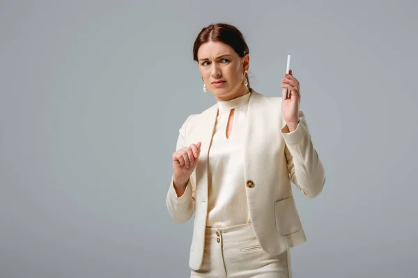 灰色で隔離されたスマートフォンを見て混乱したビジネス女性 — ストック写真