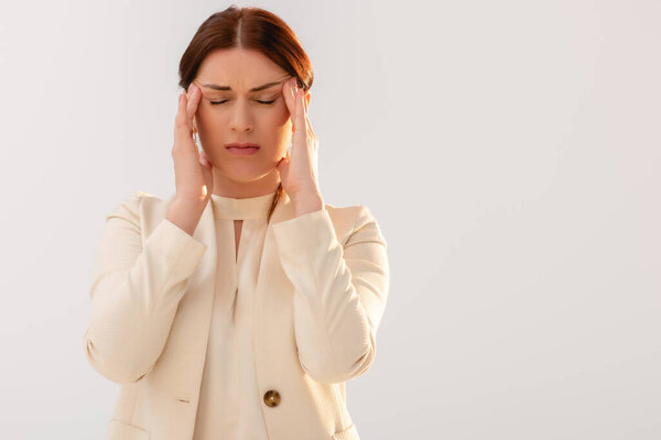Beautiful businesswoman suffering from migraine isolated on grey 