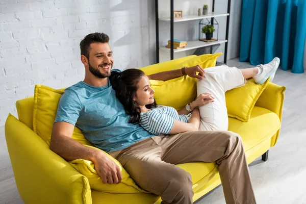 Sorrindo Homem Olhando Para Longe Perto Atraente Namorada Sofá Sala — Fotografia de Stock