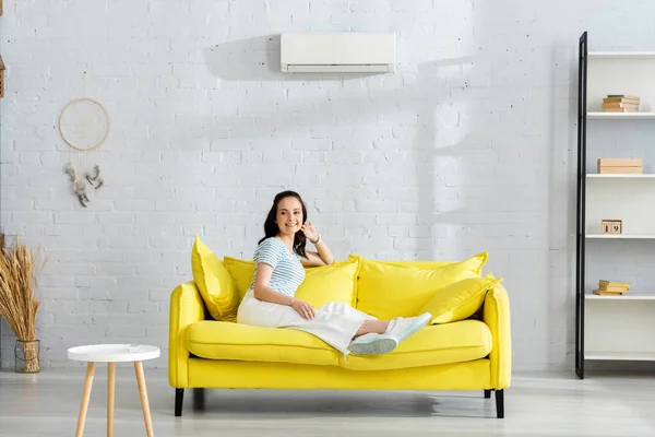 Lächelndes Mädchen Blickt Auf Couch Neben Fernbedienung Der Klimaanlage Auf — Stockfoto
