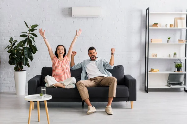 Positivt Par Ler Och Visar Gest När Sitter Soffan Hemma — Stockfoto