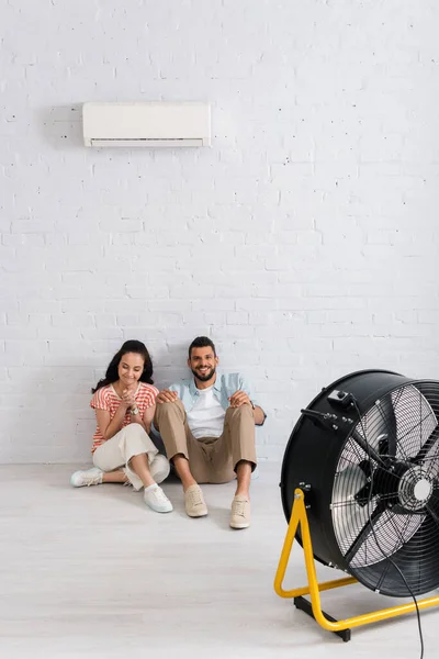 Positive Couple Sitting Floor Air Conditioner Electric Fan — Stock Photo, Image