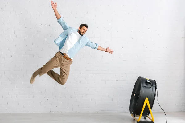 Handsome Bearded Man Jumping Electric Fan Home — Stock Photo, Image