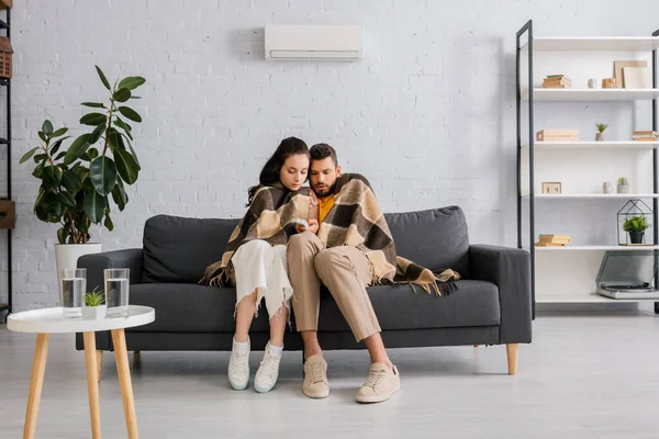 Young Couple Wrapped Plaid Holding Remote Controller Air Conditioner Living — Stock Photo, Image