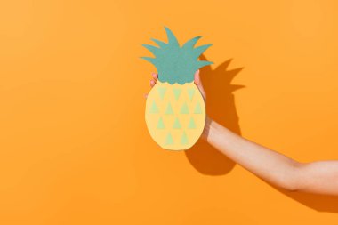 Kırpılmış portakallı kağıttan ananas tutan genç kadın manzarası. 