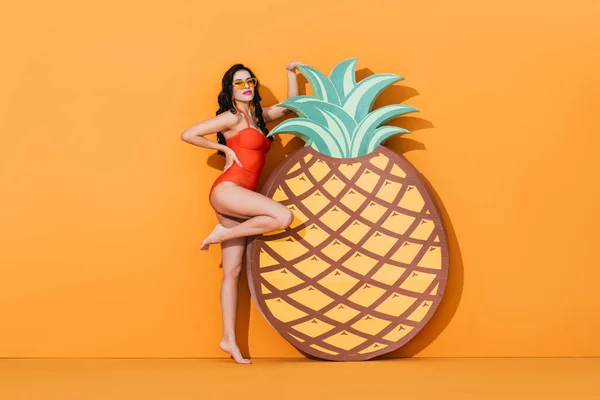 수영복을 매력적 여자가 컨셉인 오렌지 파인애플을 근처에서 손으로 허리에 선글라스를 — 스톡 사진
