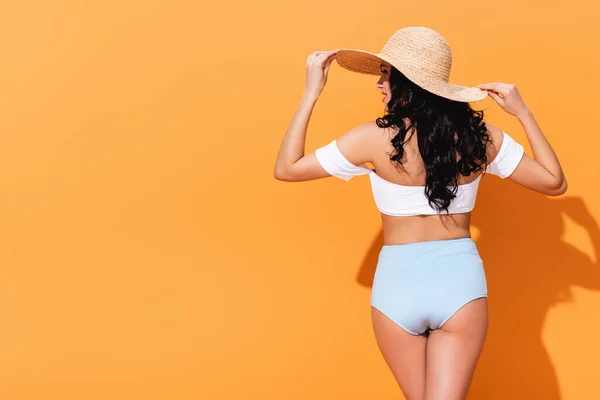 戴着草帽站在橙色上的快乐而时髦的女孩 — 图库照片