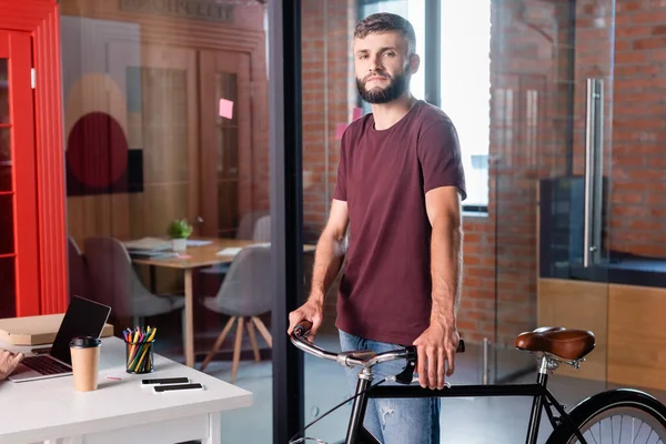 Γενειοφόρος Επιχειρηματίας Στέκεται Ποδήλατο Στο Σύγχρονο Γραφείο — Φωτογραφία Αρχείου