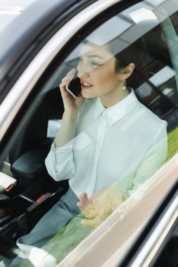 İş kadınının arabada akıllı telefondan konuşmasının seçici odak noktası 