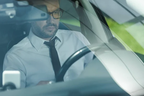 Selective focus of businessman in formal wear driving car