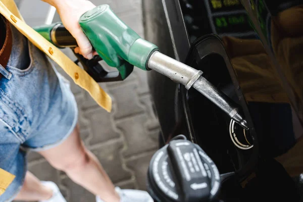 ガソリンスタンドの車の近くに燃料ノズルを保持している女性の作物ビュー — ストック写真