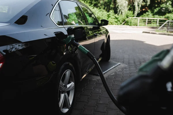 ガソリンスタンドでの自動車のオープンガスタンク内の燃料ノズルの選択的な焦点 — ストック写真