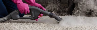 Plastik eldivenli panoramik temizlik ürünleri. Halıda sıcak buhar bulunan elektrikli süpürge kullanıyorlar. 