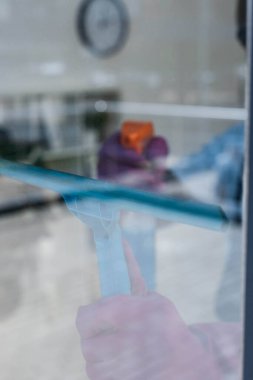 Ofisteki pencereyi temizlerken cam sapı ve deterjan kullanarak temizleyicinin seçici odağı 
