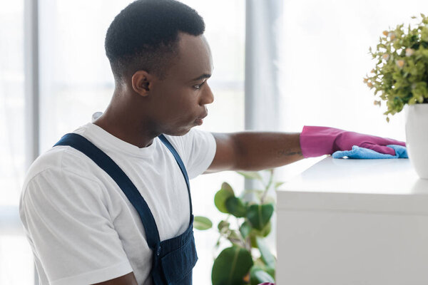 Selective focus of african american worker of office cleaning service cleaning cupboard with rag 
