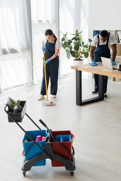 Focus Selettivo Detergenti Multietnici Lavare Pavimenti Tavoli Mentre Lavora Ufficio — Foto Stock