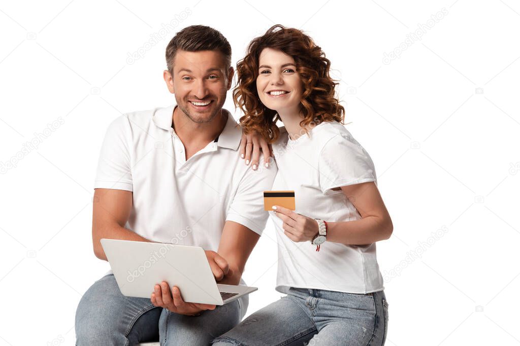 happy man with laptop near curly wife holding credit card isolated on white 