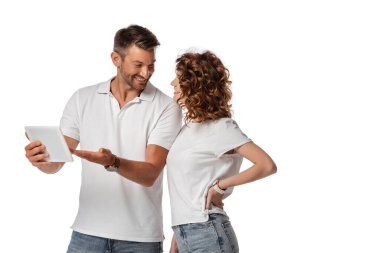 Neşeli adam dijital tableti işaret ediyor ve beyaz tenli kadına bakıyor. 