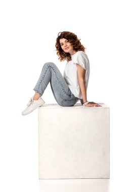 Küp üzerinde oturan mutlu kadın ve beyaz üzerinde izole bir şekilde gülümseyen. 