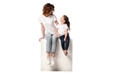 Mutlu anne ve kız beyazın üzerinde otururken birbirlerine bakıyorlar.