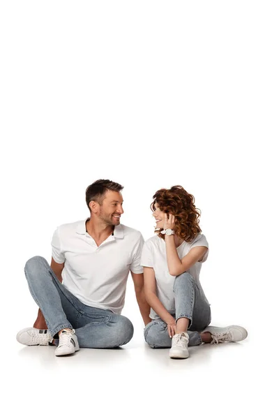 快乐的一对穿着斜纹棉布牛仔裤的情侣坐在一起 面面相觑 — 图库照片
