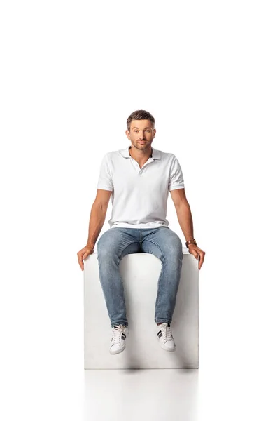 Homem Bonito Jeans Jeans Sentado Cubo Olhando Para Câmera Branco — Fotografia de Stock